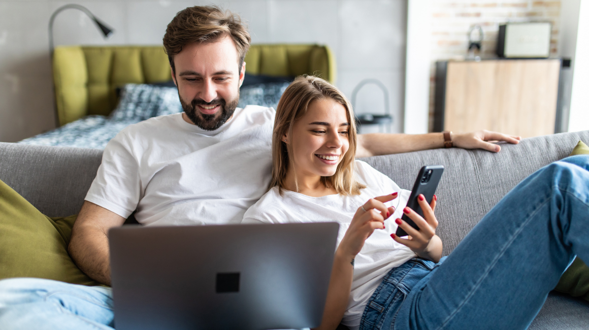 Para relaksująca się na kanapie z laptopem i telefonem